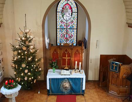 Weihnachtlich geschmückter Innenraum der kleinen Holzkirche
